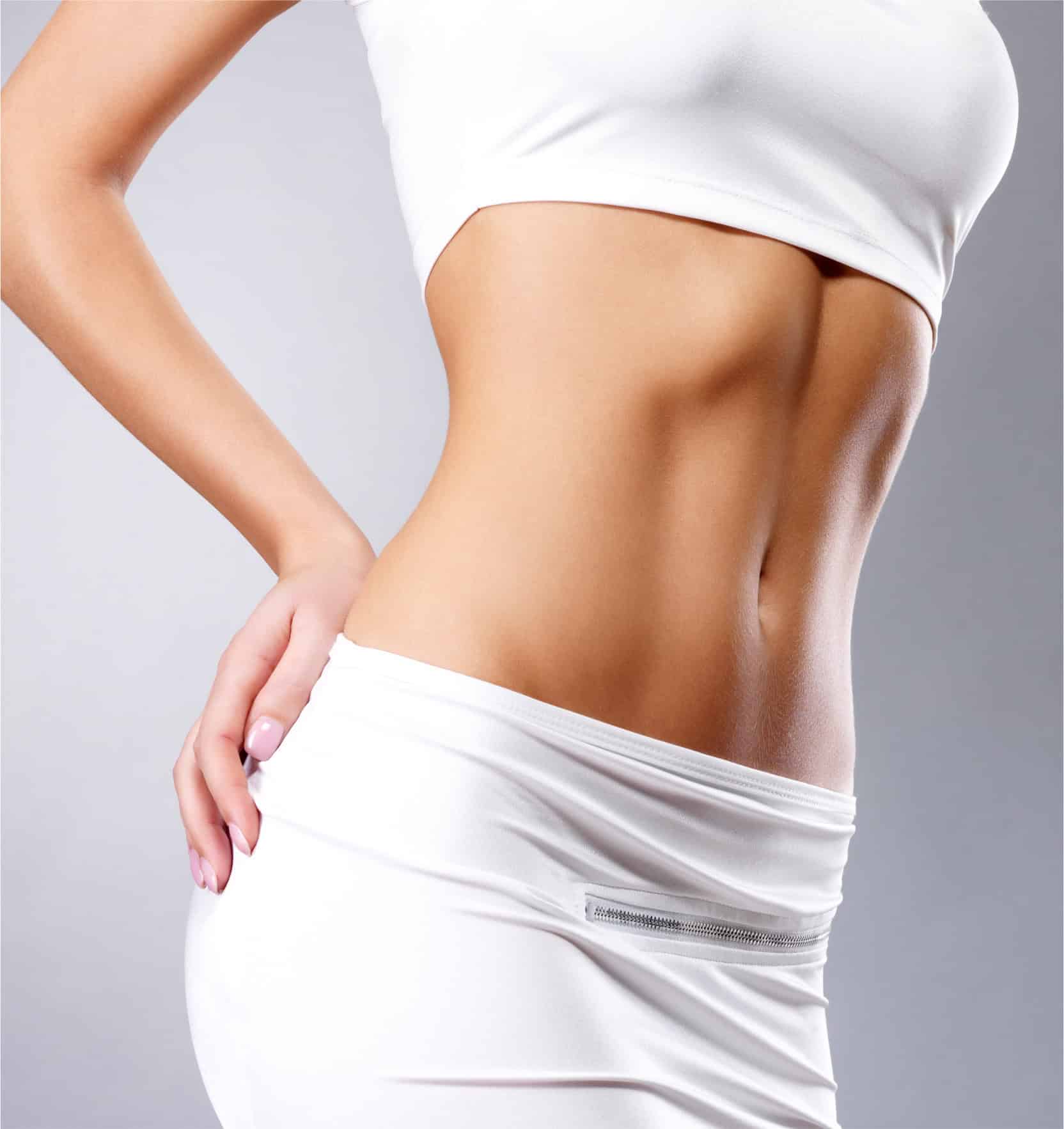 Woman with toned abdomen in white sportswear, showcasing body contouring.