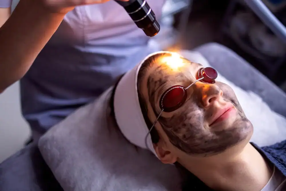Woman receiving facial treatment with LED light therapy at Dolce Aesthetics clinic.